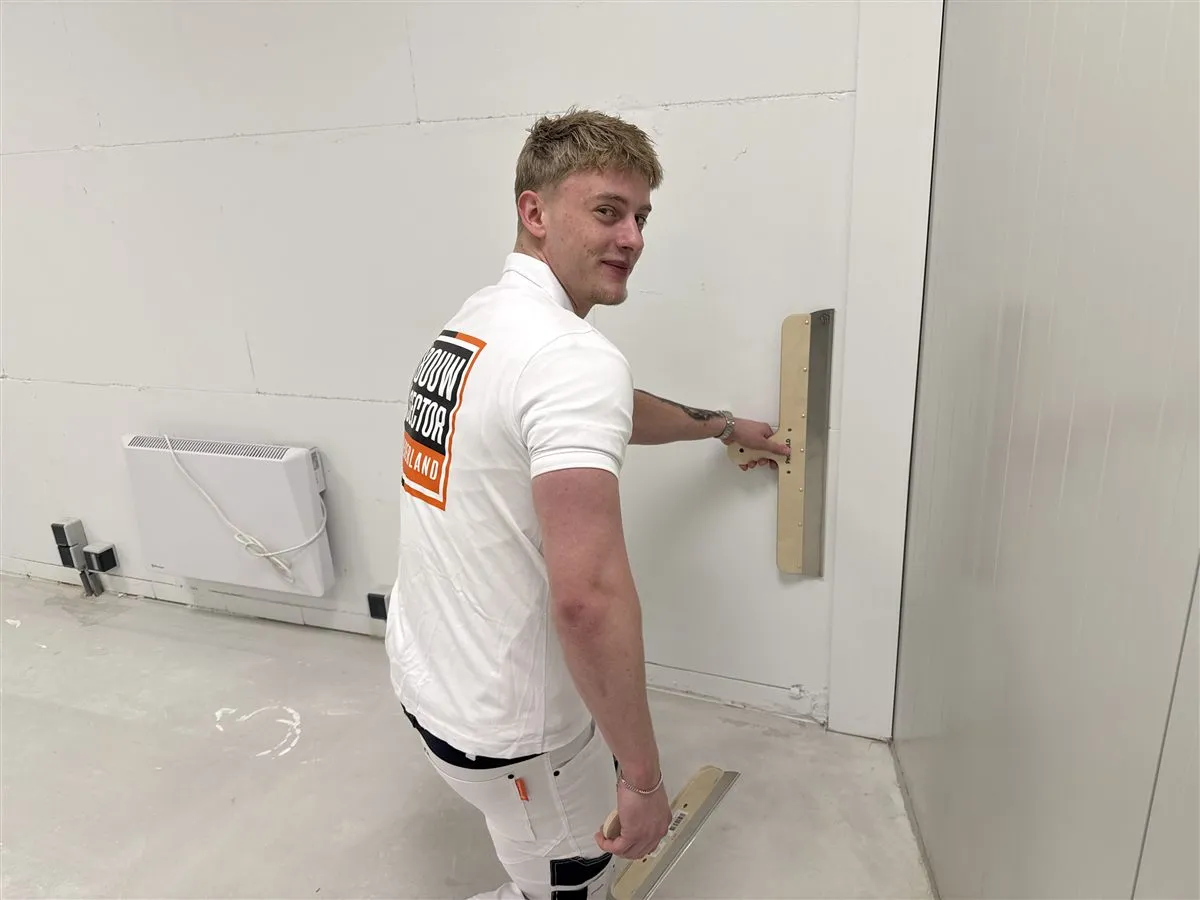 Stukadoor Bram van Bouwsector Nederland met een spaan tegen een witte wand