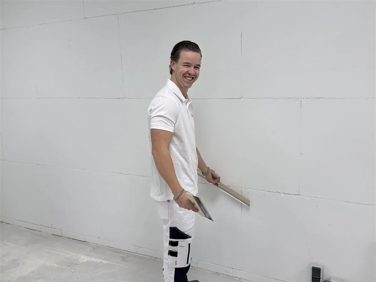 Vakman Chris van Bouwsector Nederland met een spaan in de hand voor een kale wand